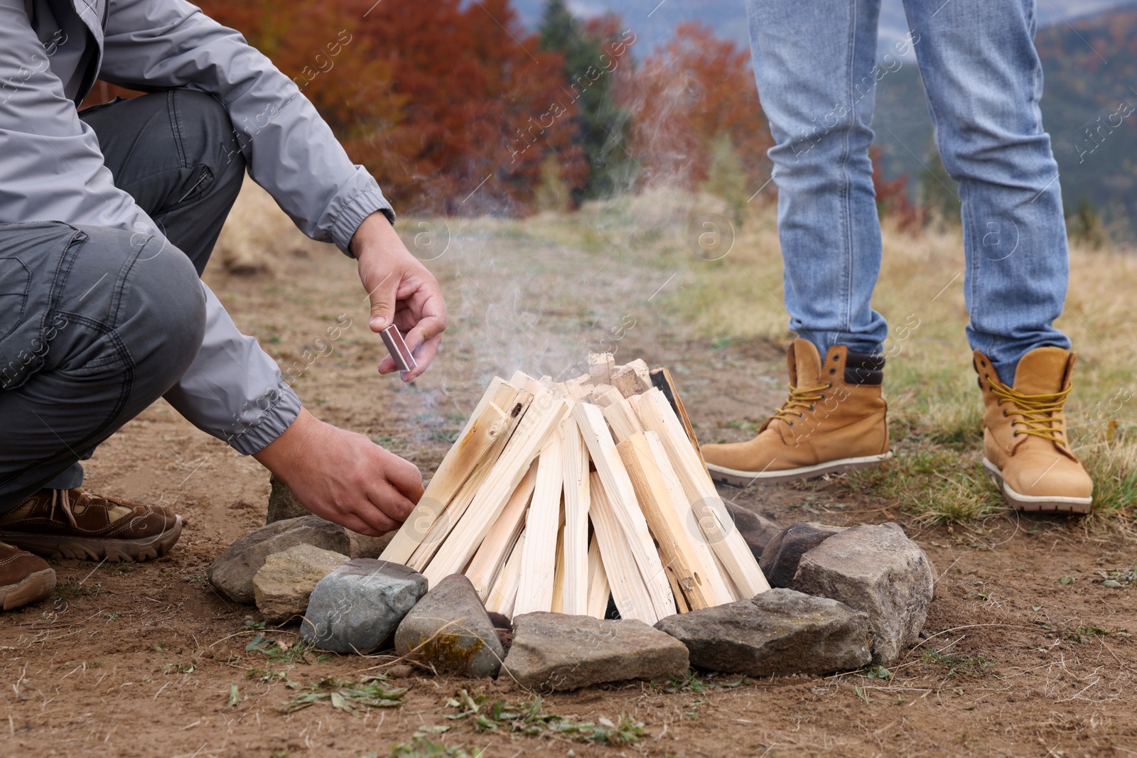 Photo of Men making bonfire outdoors, closeup. Camping season