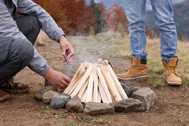 Men making bonfire outdoors, closeup. Camping season