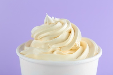 Cup with tasty frozen yogurt on violet background, closeup