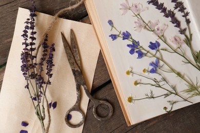 Photo of Old scissors with beautiful dried flowers and book on wooden table, flat lay
