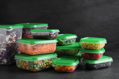 Photo of Set of plastic containers with fresh food on black table