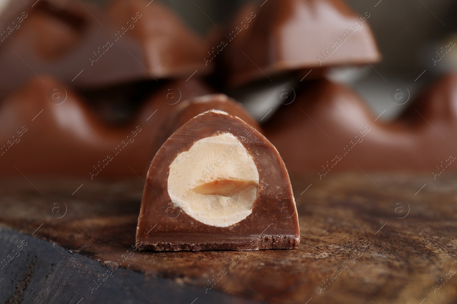 Photo of Tasty chocolate bar with nuts on wooden board, closeup