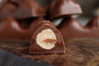 Tasty chocolate bar with nuts on wooden board, closeup