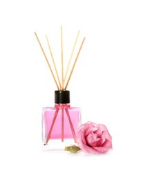 Photo of Aromatic reed air freshener and rose on white background