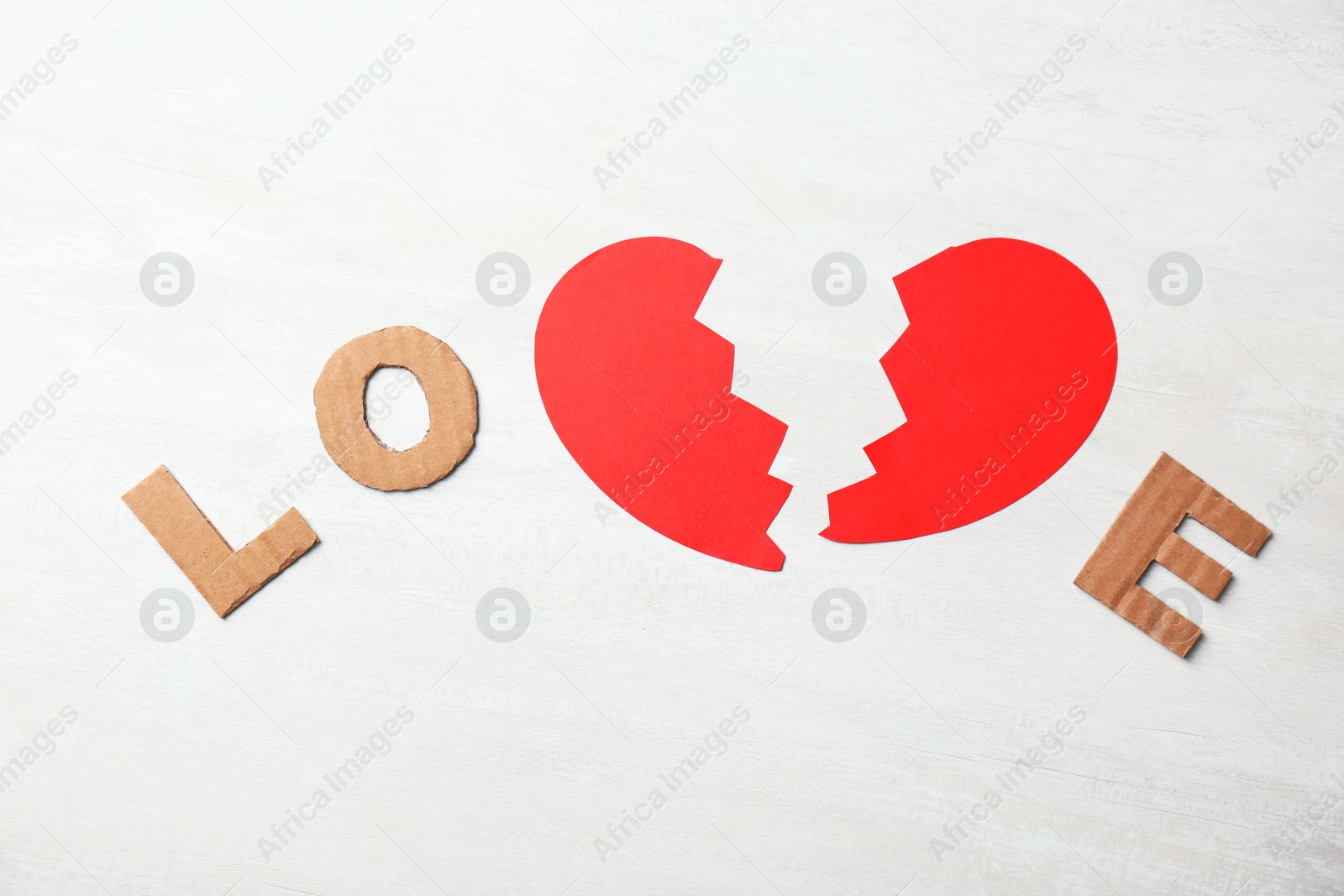 Photo of Word "Love" with cut paper heart and cardboard letters on light background, top view. Relationship problems
