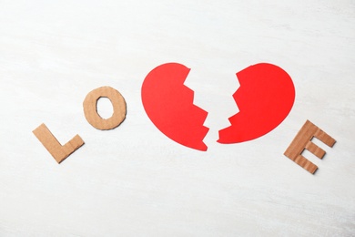 Word "Love" with cut paper heart and cardboard letters on light background, top view. Relationship problems