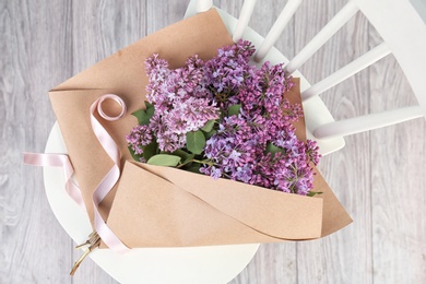 Beautiful blossoming lilac on chair indoors, top view. Spring flowers