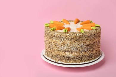 Dish with tasty carrot cake on pink background, space for text