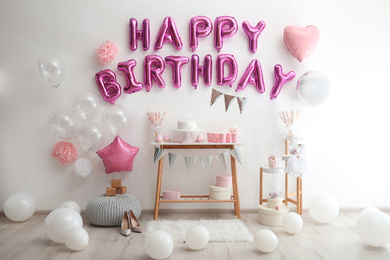 Photo of Phrase HAPPY BIRTHDAY made of pink balloon letters in decorated room