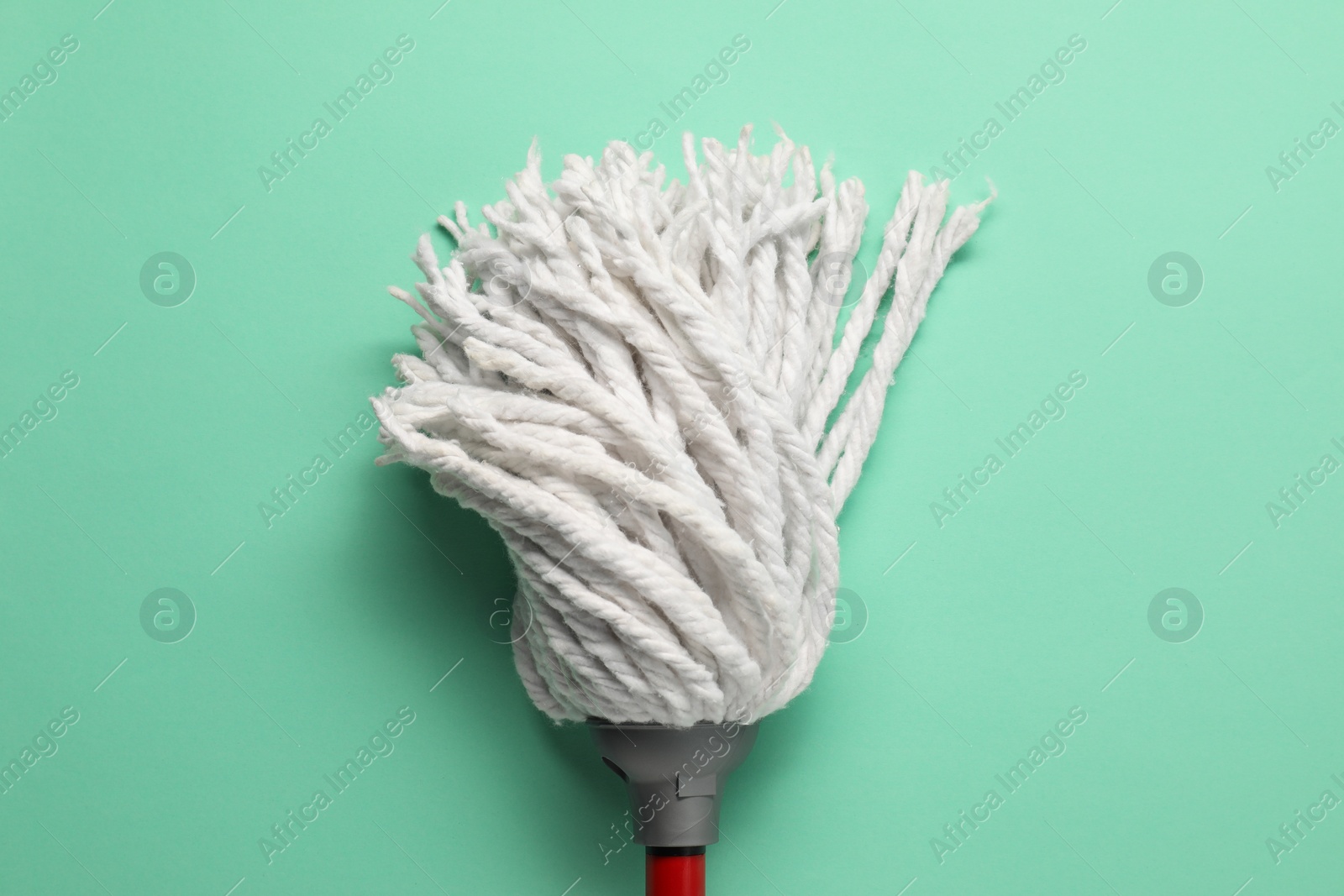 Photo of Mop with plastic handle on turquoise background, top view