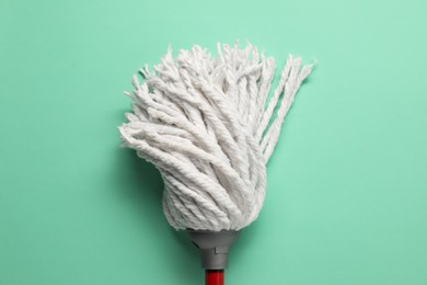 Photo of Mop with plastic handle on turquoise background, top view