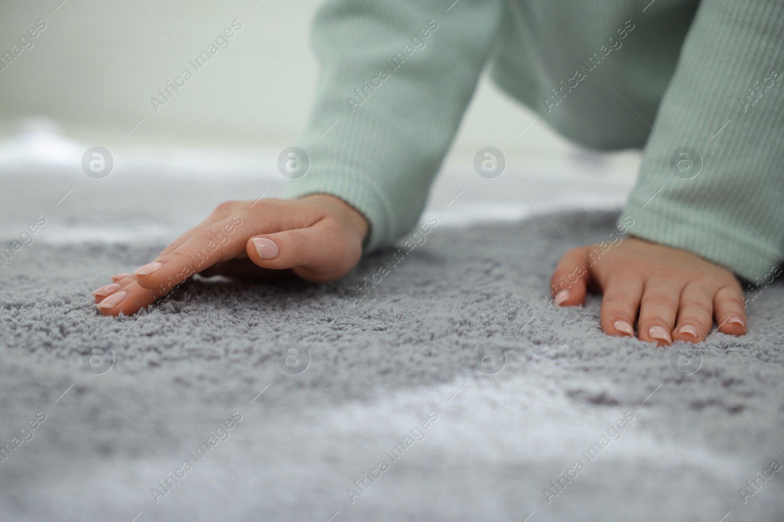 Photo of Woman touching soft grey carpet indoors, closeup