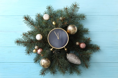 Photo of Stylish clock and Christmas decor on light blue wooden background, top view. New Year countdown