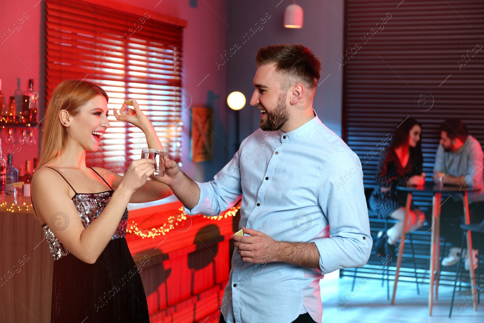 Photo of Young couple drinking Mexican Tequila shots in bar