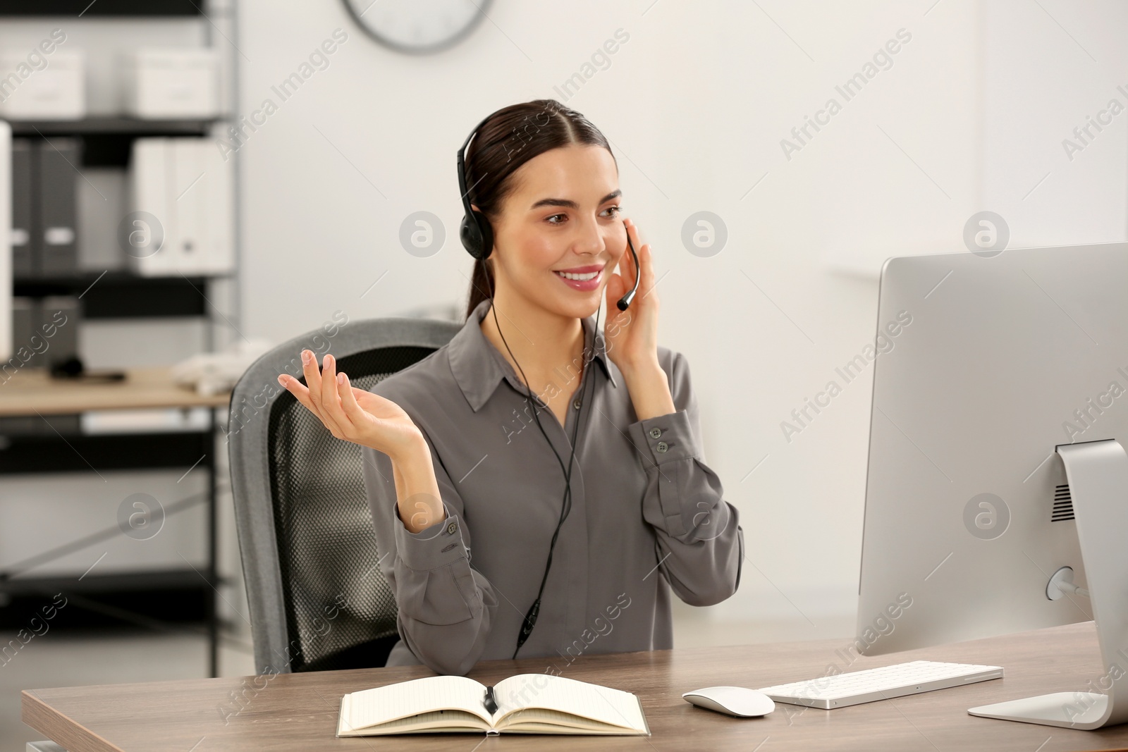 Photo of Hotline operator with headset working on computer in office