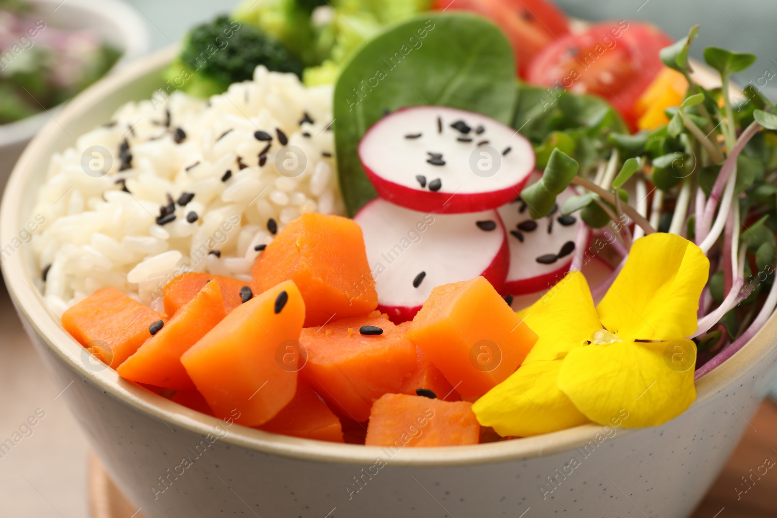 Photo of Bowl with many different vegetables and rice on wooden table, closeup. Vegan diet