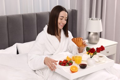 Smiling woman having breakfast in bed at home