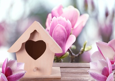 Image of Beautiful bird house on wooden table outdoors