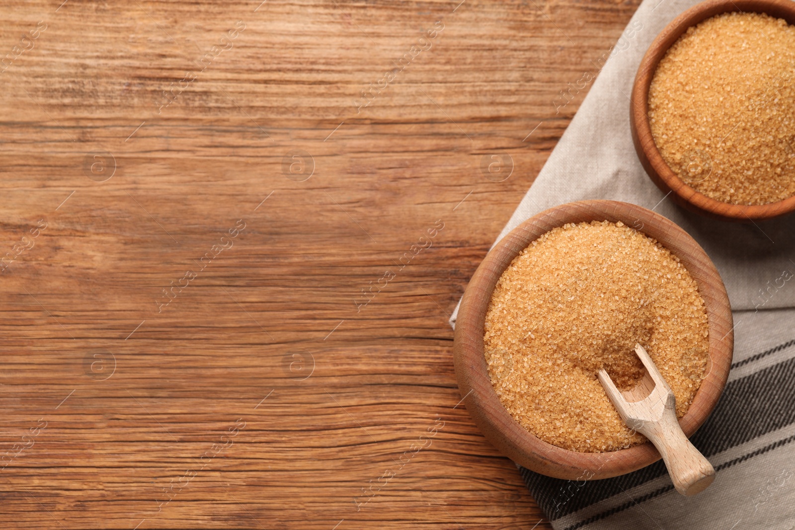 Photo of Brown sugar in bowls on wooden table, flat lay. Space for text