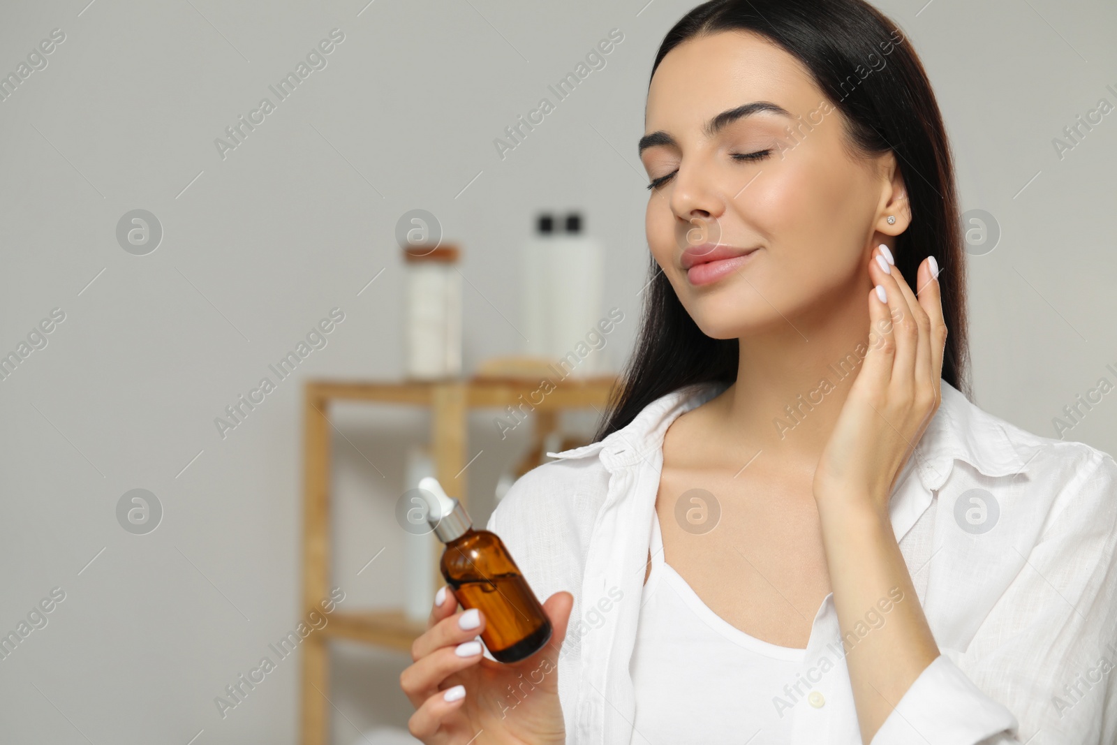 Photo of Young woman with bottle of essential oil indoors