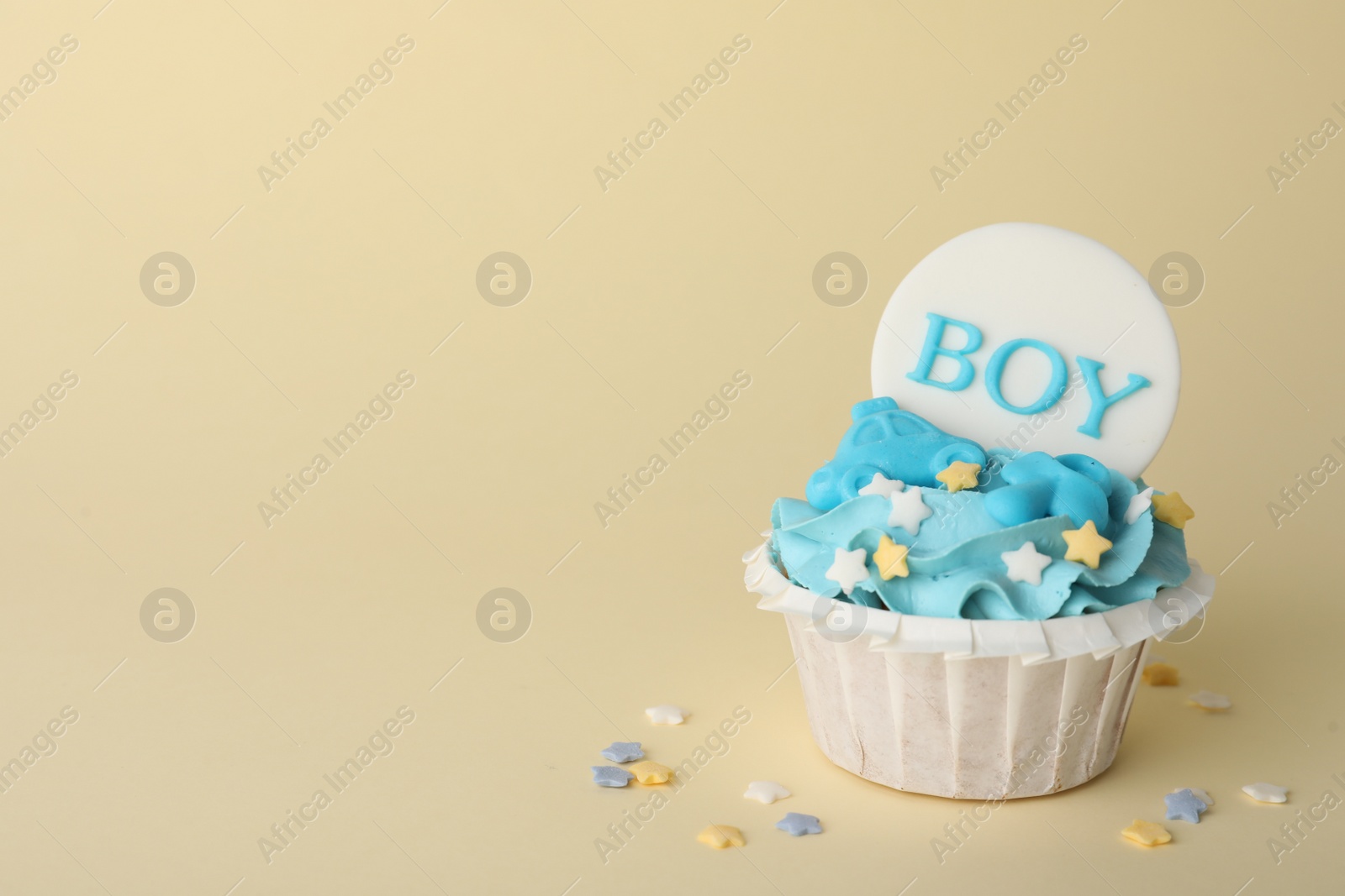 Photo of Delicious cupcake with light blue cream and Boy topper on beige background, space for text. Baby shower party