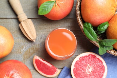 Photo of Tasty freshly made grapefruit juice and fruits on wooden table, flat lay