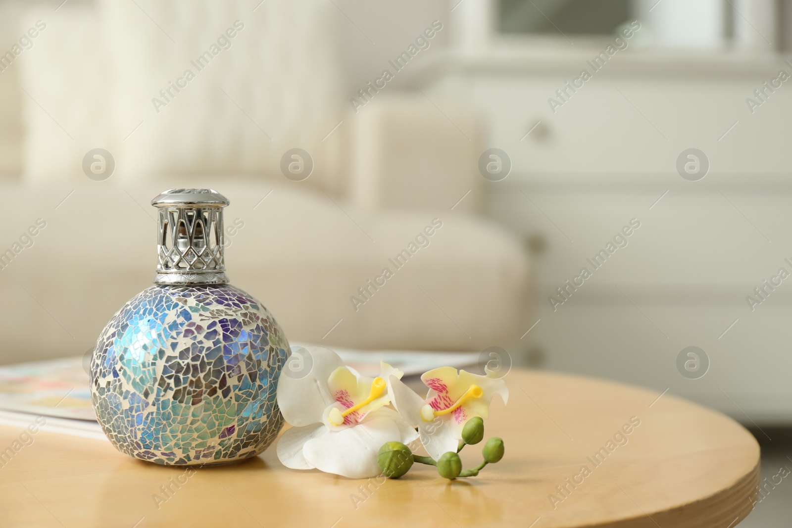 Photo of Stylish catalytic lamp with orchid on wooden table in living room, space for text. Cozy interior