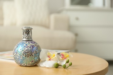 Stylish catalytic lamp with orchid on wooden table in living room, space for text. Cozy interior