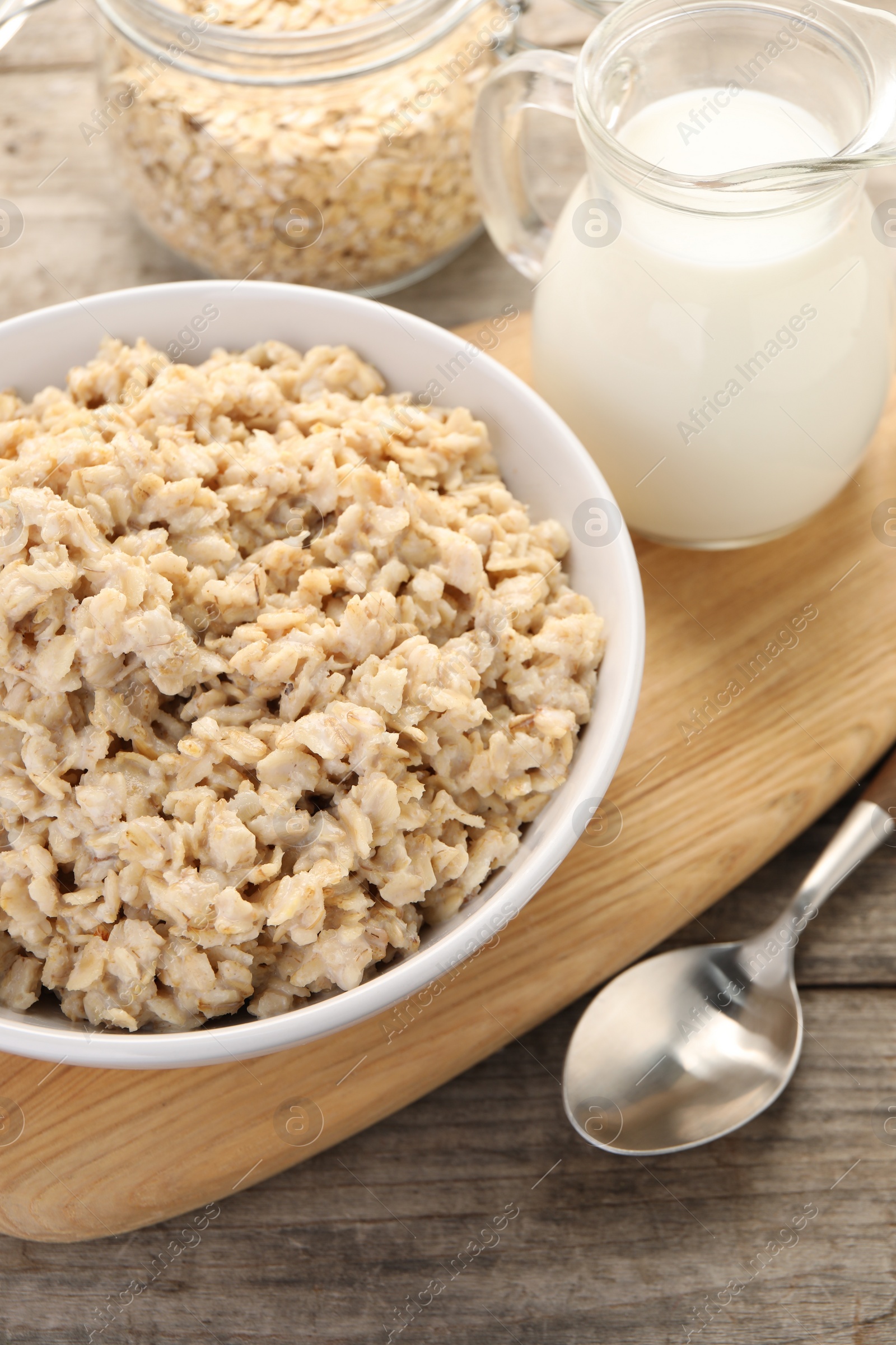 Photo of Tasty boiled oatmeal in bowl served on wooden table