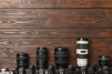 Photo of Modern cameras on wooden table, flat lay. Space for text