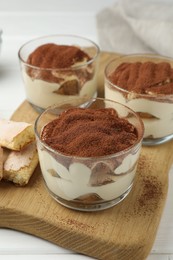 Delicious tiramisu in glasses and cookies on table