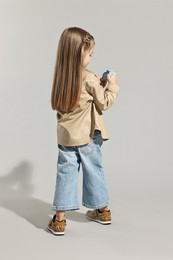 Photo of Fashion concept. Stylish girl with toy camera on light grey background