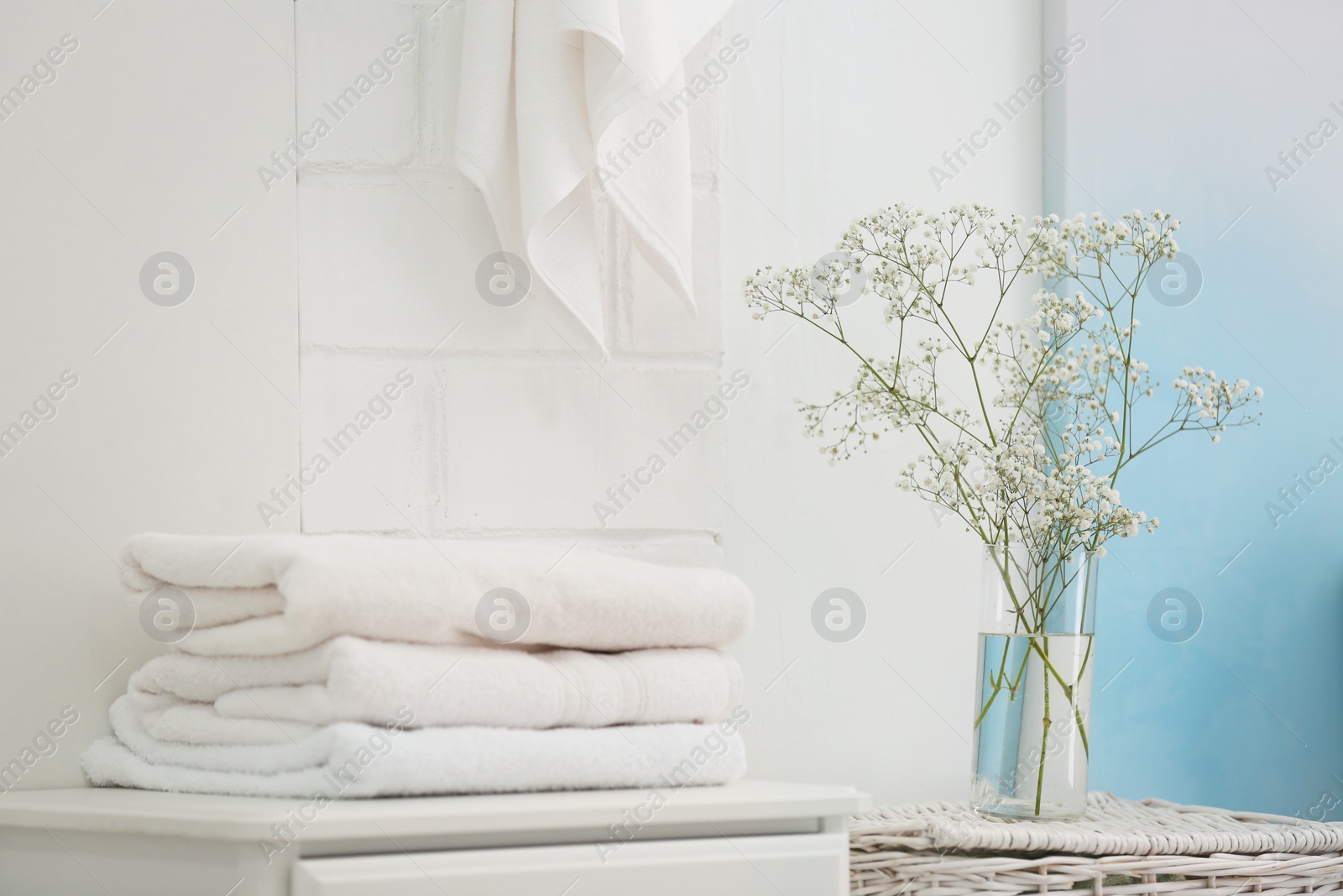 Photo of Fresh clean towels and vase with flowers in bathroom