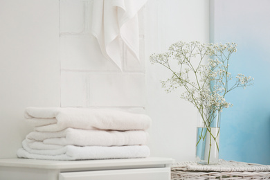 Fresh clean towels and vase with flowers in bathroom