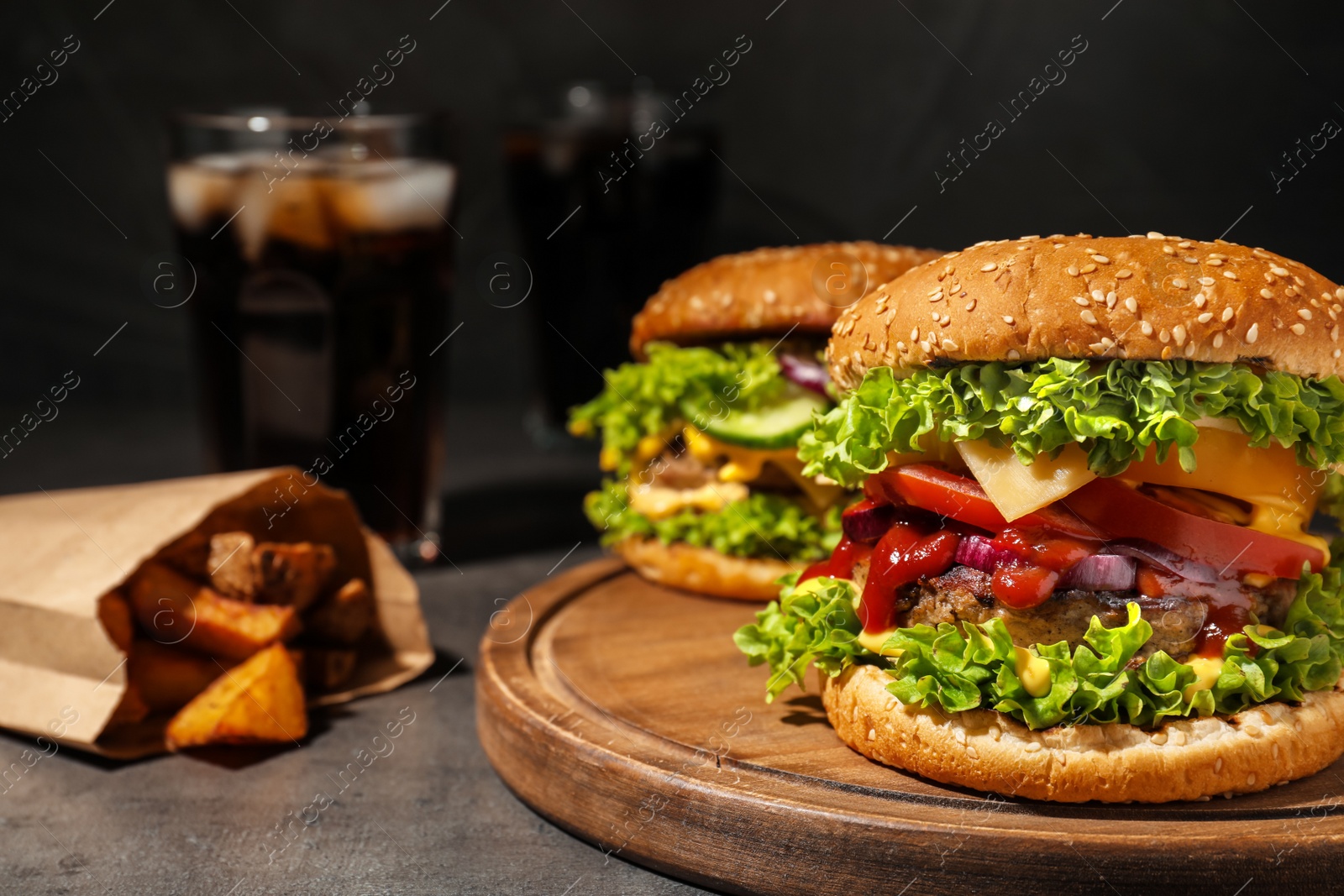 Photo of Tasty burgers and fried potatoes on table. Space for text