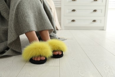 Photo of Woman in fluffy slippers at home, closeup. Space for text