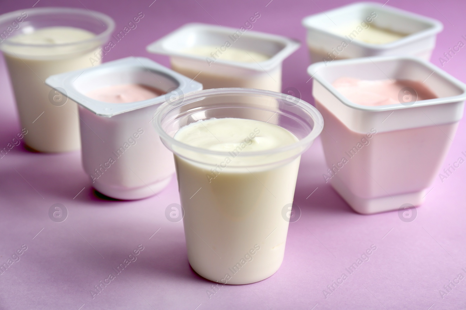 Photo of Plastic cups with tasty yogurt on color background