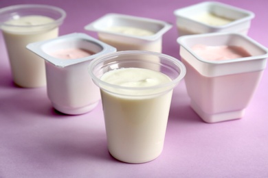 Plastic cups with tasty yogurt on color background