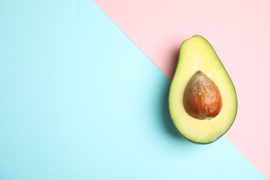 Photo of Cut fresh ripe avocado on color background, top view with space for text