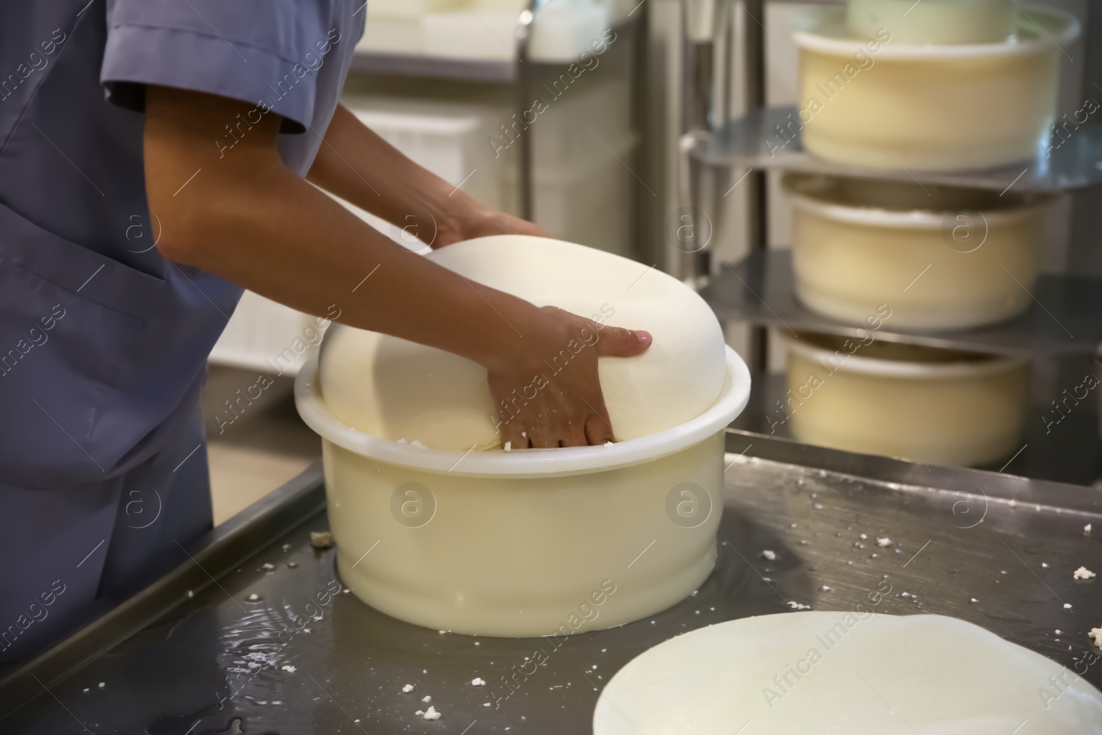 Photo of Worker taking fresh cheese from mould at modern factory, closeup