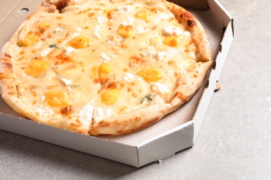 Photo of Carton box with hot cheese pizza Margherita on grey table, closeup