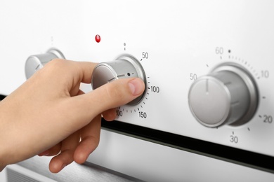 Photo of Woman adjusting electric oven, closeup. Kitchen appliance
