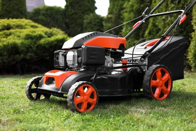 Modern lawn mower on green grass in garden