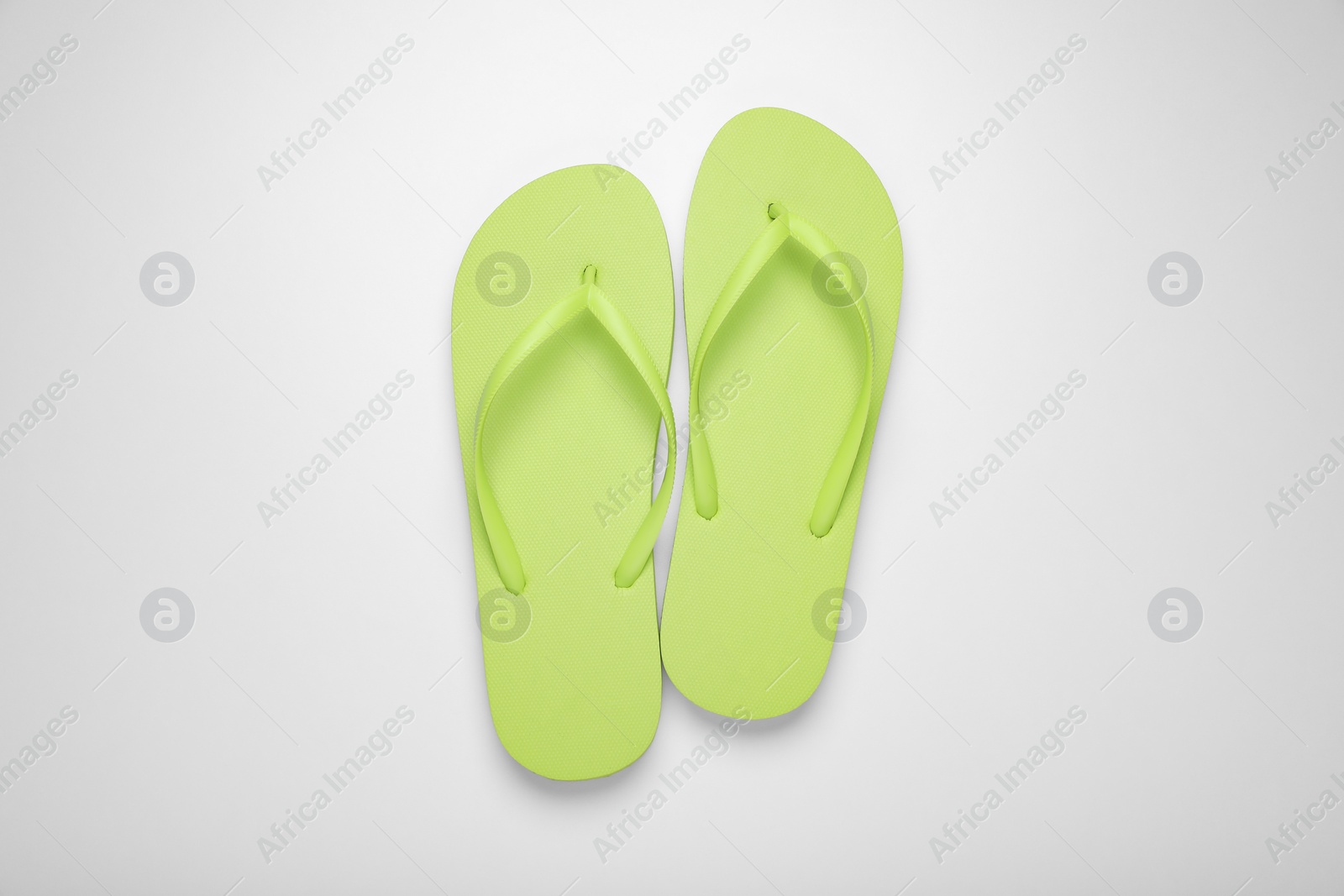 Photo of Light green flip flops on white background, top view