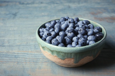 Photo of Crockery with juicy and fresh blueberries on wooden table