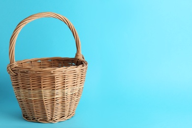 Photo of Empty wicker basket on light blue background, space for text. Easter item