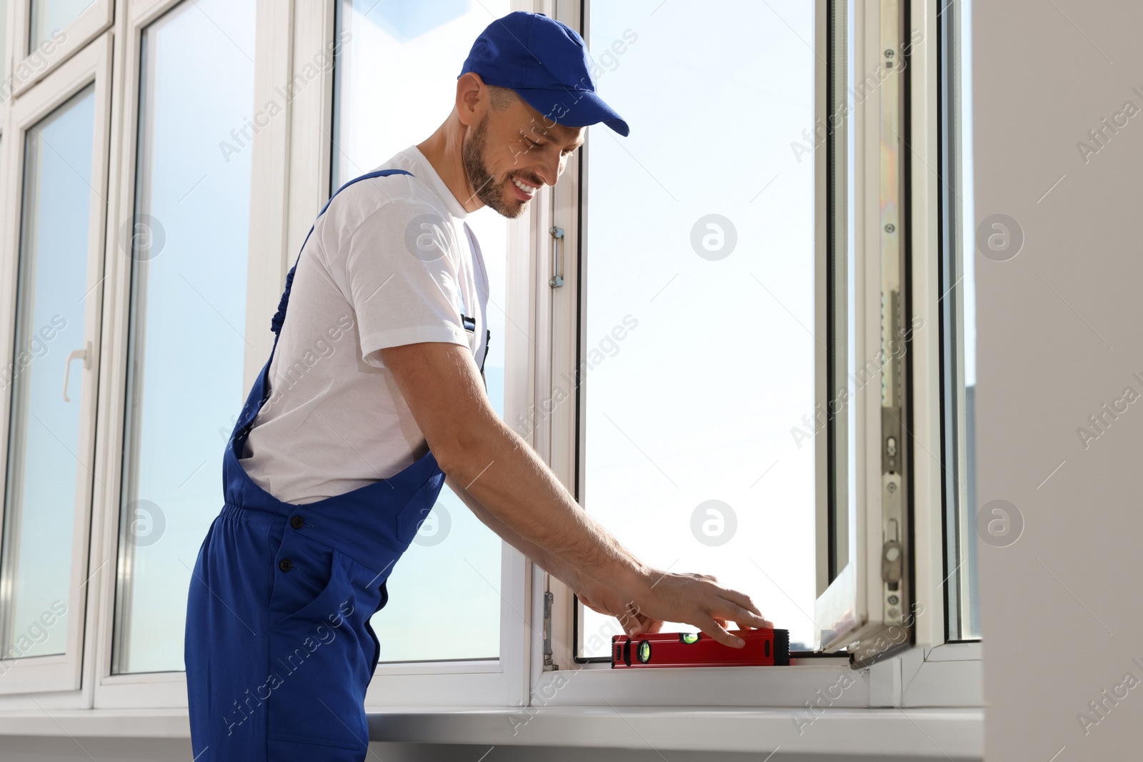 Photo of Worker using bubble level after plastic window installation indoors