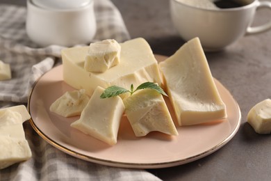 Photo of Pieces of tasty white chocolate and mint on grey table, closeup
