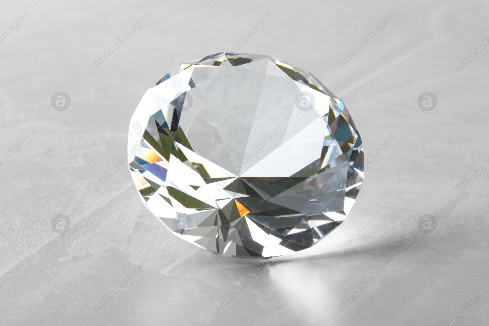 Photo of Beautiful shiny diamond on gray table, closeup