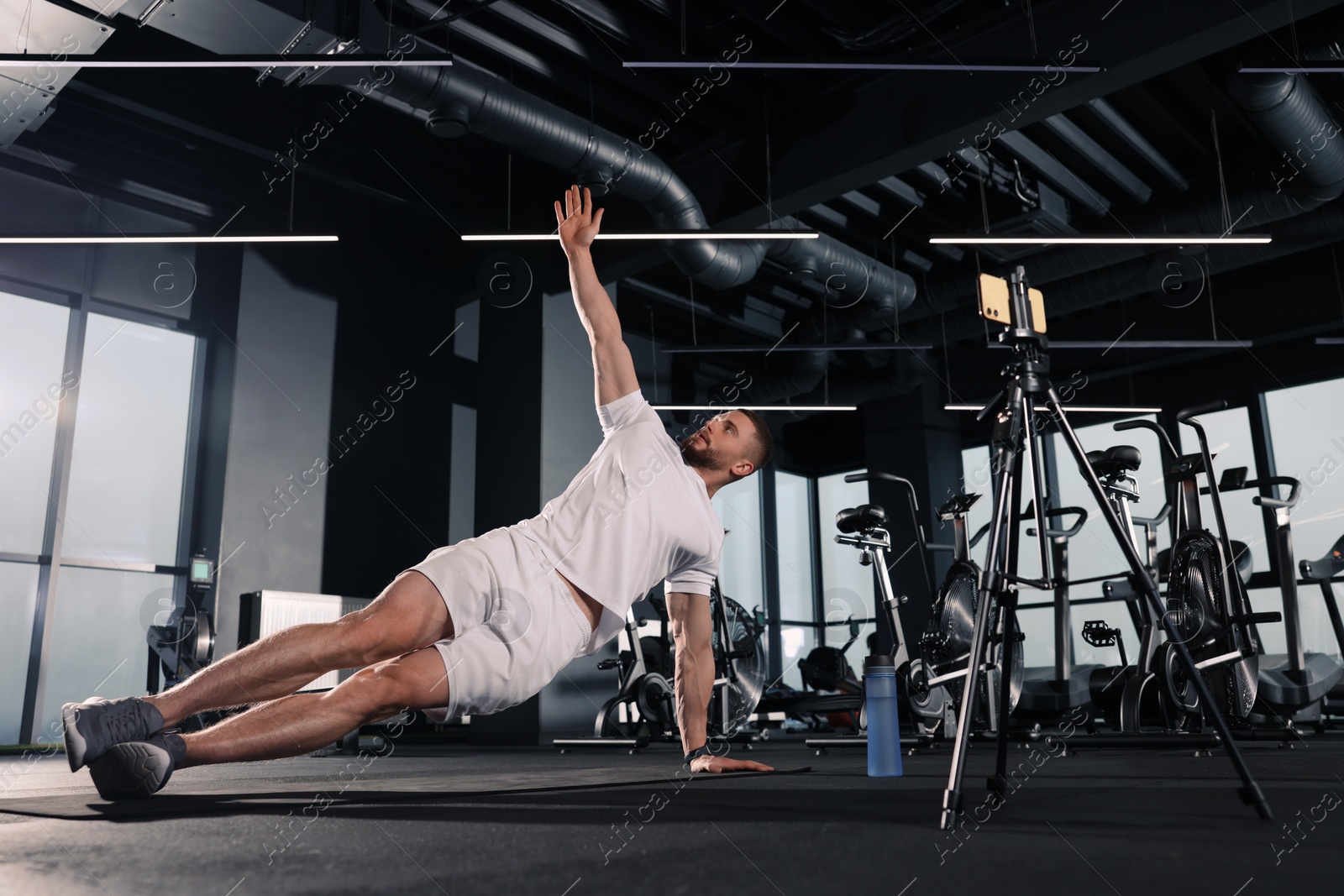 Photo of Trainer streaming online workout with phone at gym